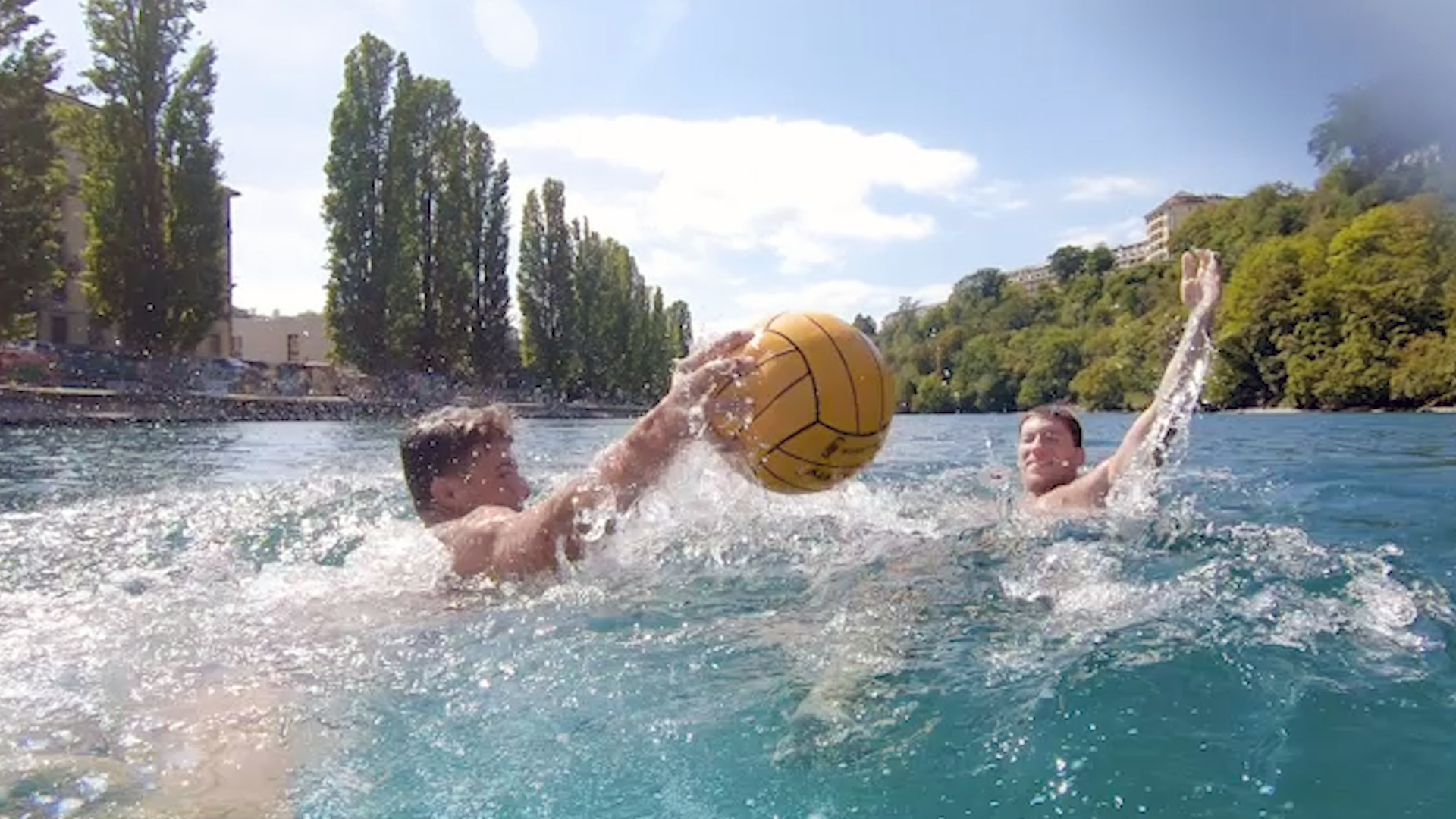 Two men playing with a ball in a river