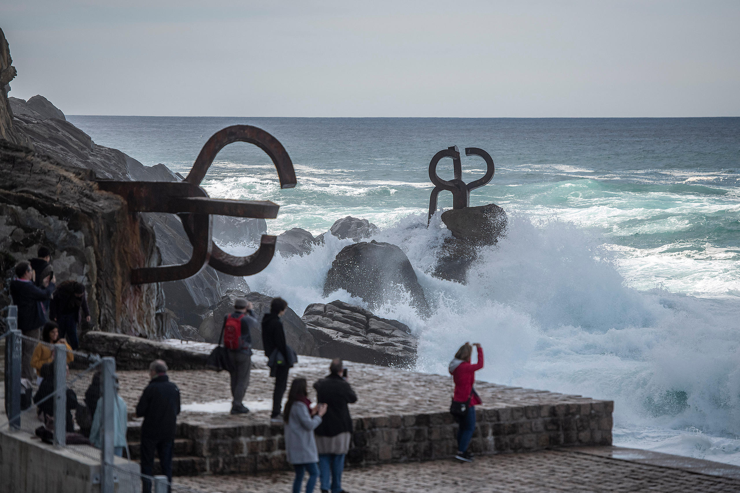 Las olas rompen contra las rocas y la escultura El Peine del viento en un extremo de la bahía de La Concha, en San Sebastián