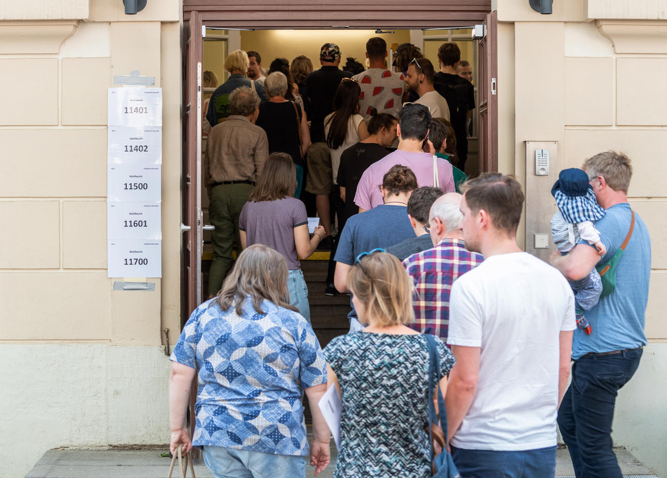 Bürgerinnen und Bürger von Dresden stehen vor einem Wahllokal Schlange