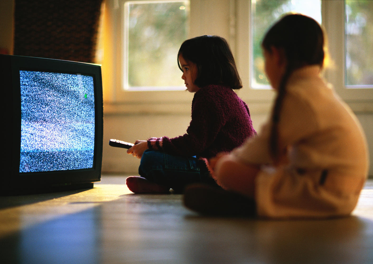 Deux enfants devant un poste de télévision neigeux