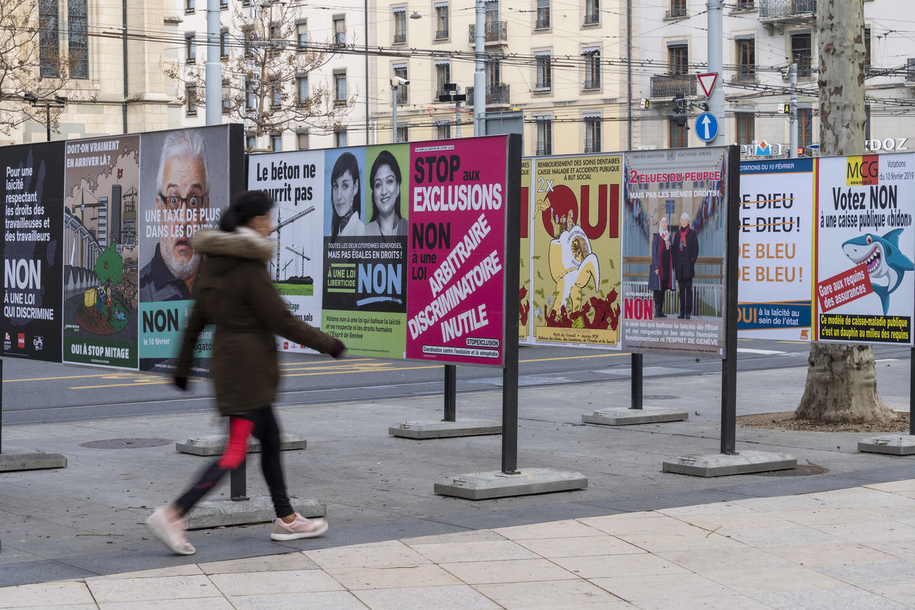 passante davanti a una serie di cartelloni per le votazioni