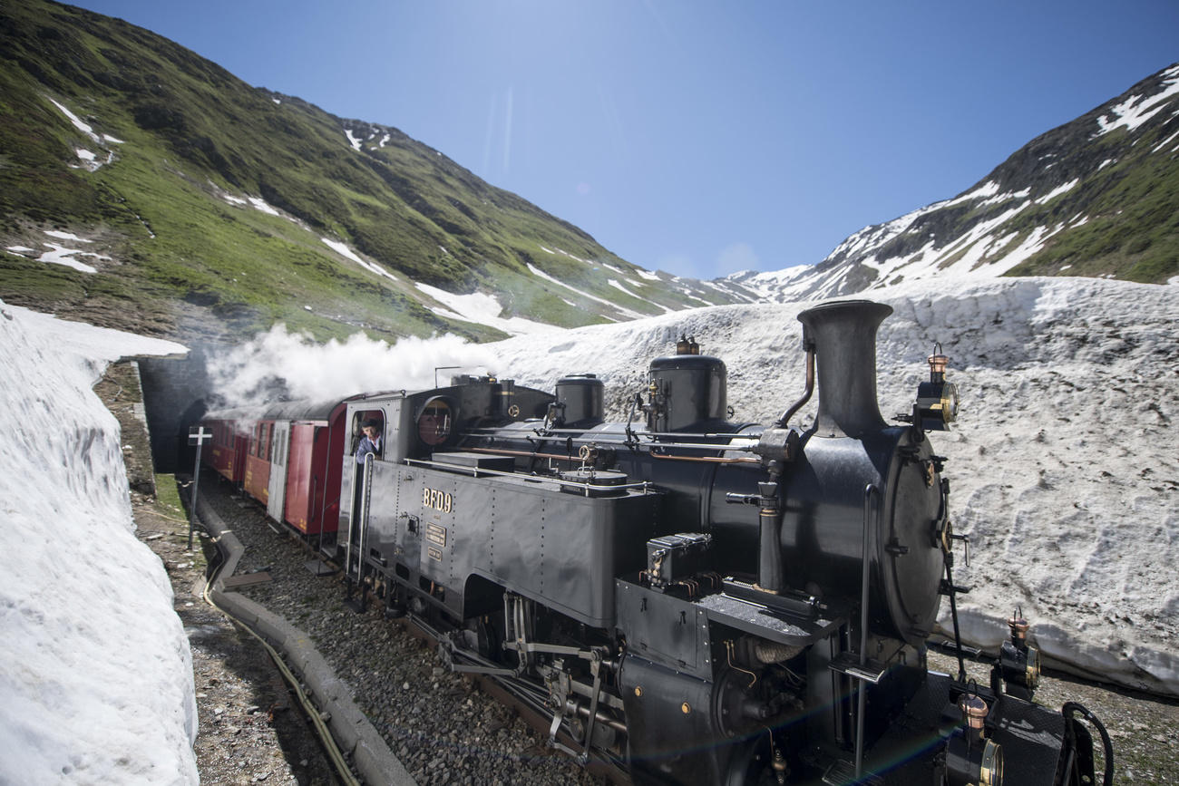 Steam train on the track with snow on both sides.