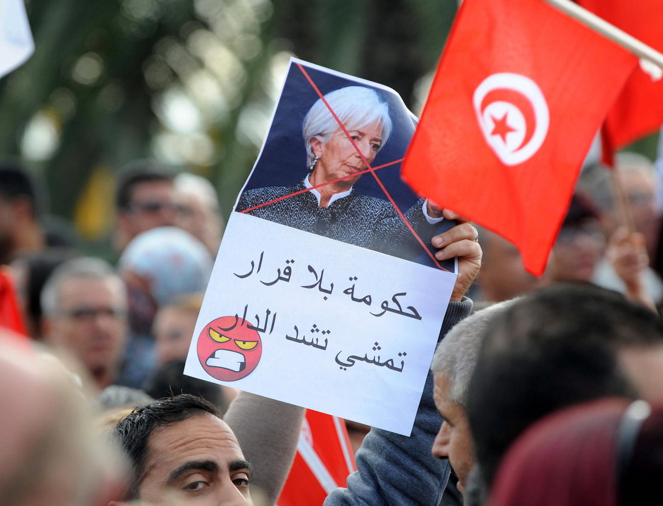 متظاهرون يرفعون علم تونس ولافتات احتجاجية