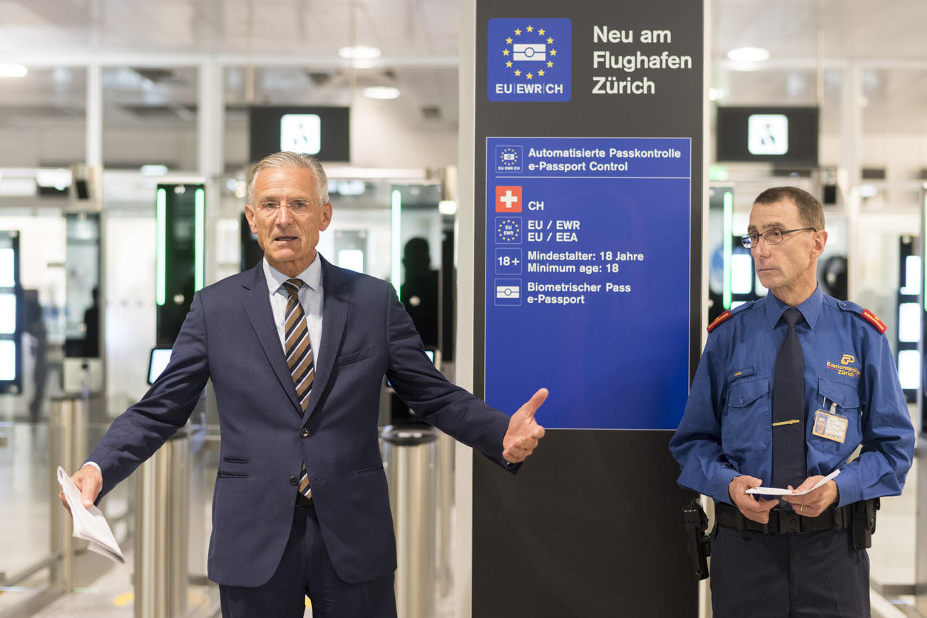 Um homem ao lado de um policial no aeroporto de Zurique