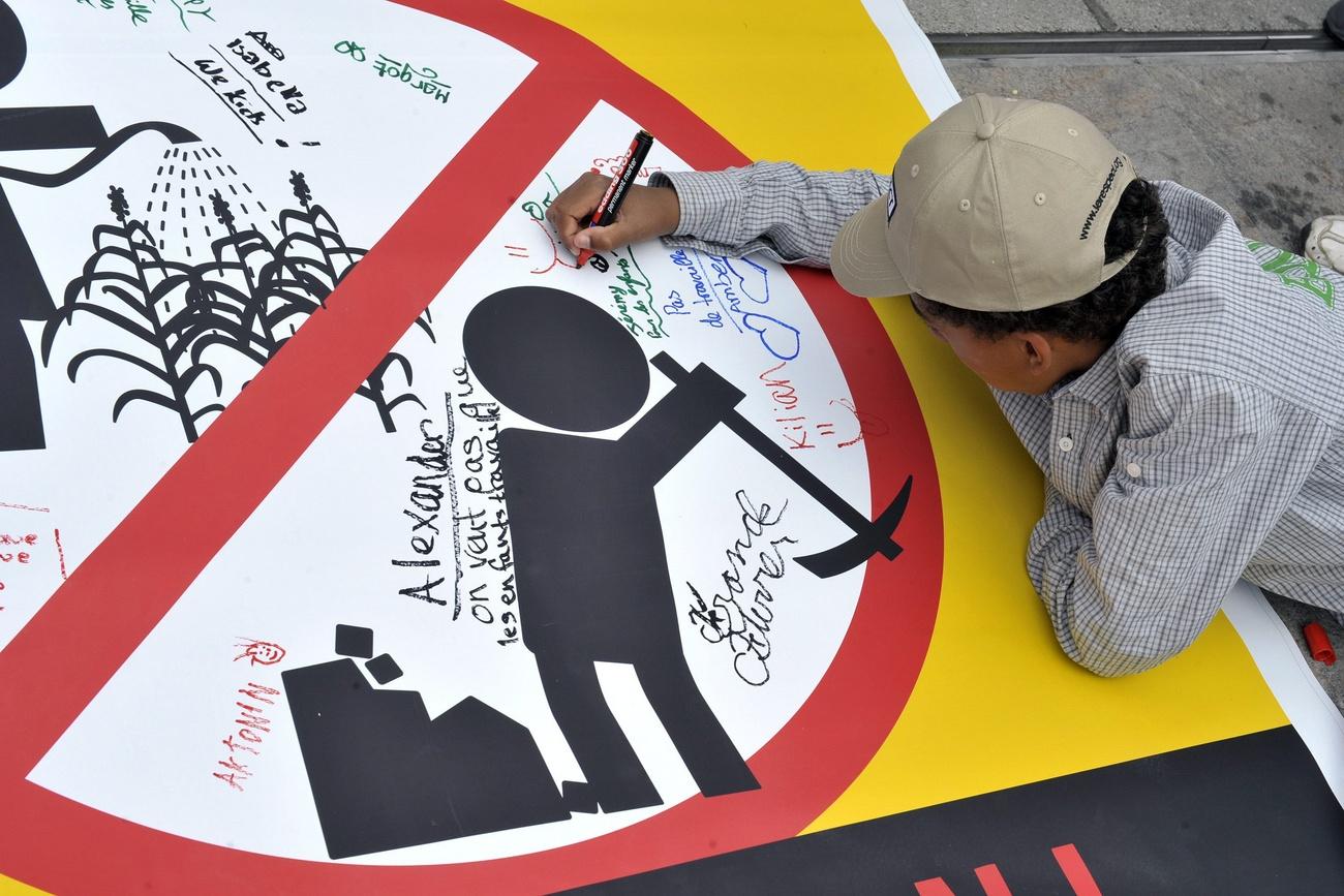 School child signs a poster in Geneva on World Day against Child Labour