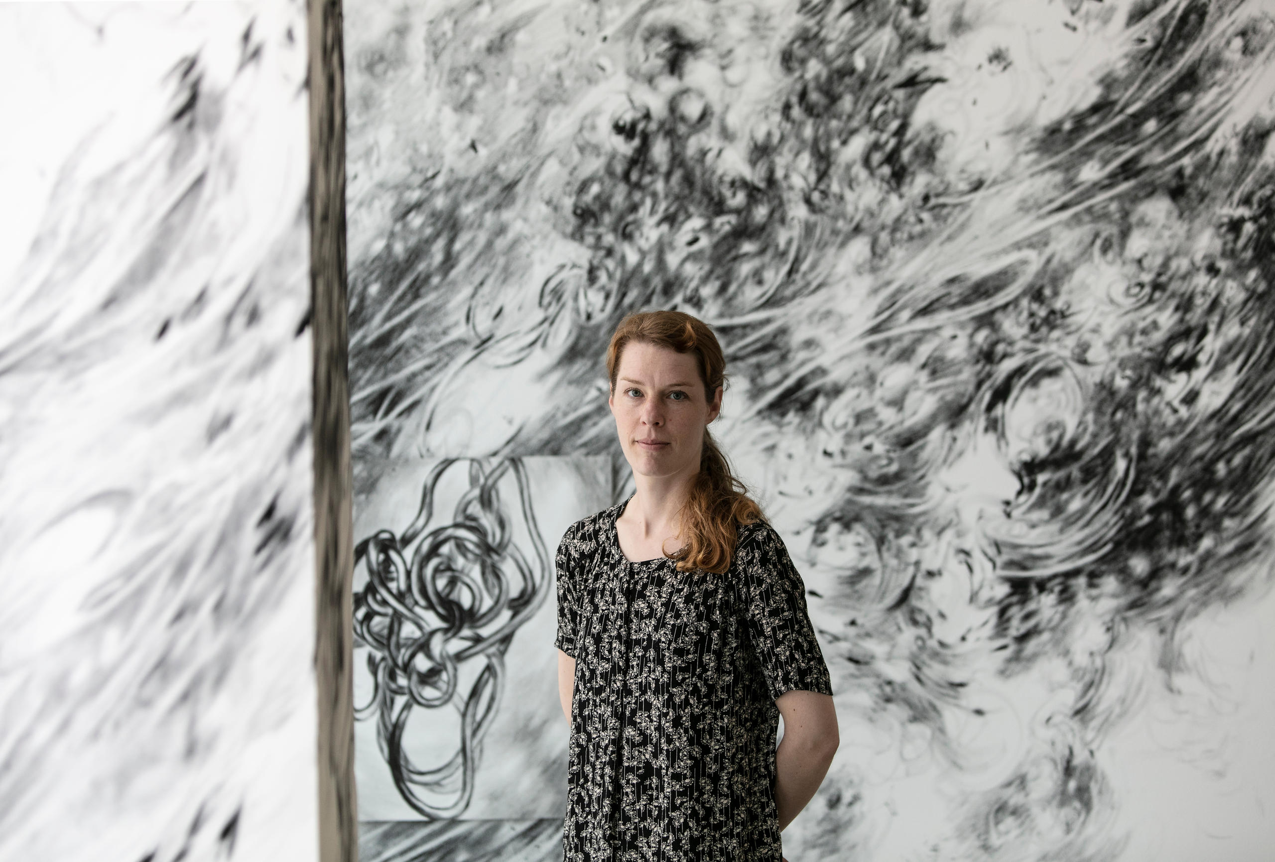 امرأة تقف أمام عمل فني من إنجازها في رواق فني بمدينة بازل