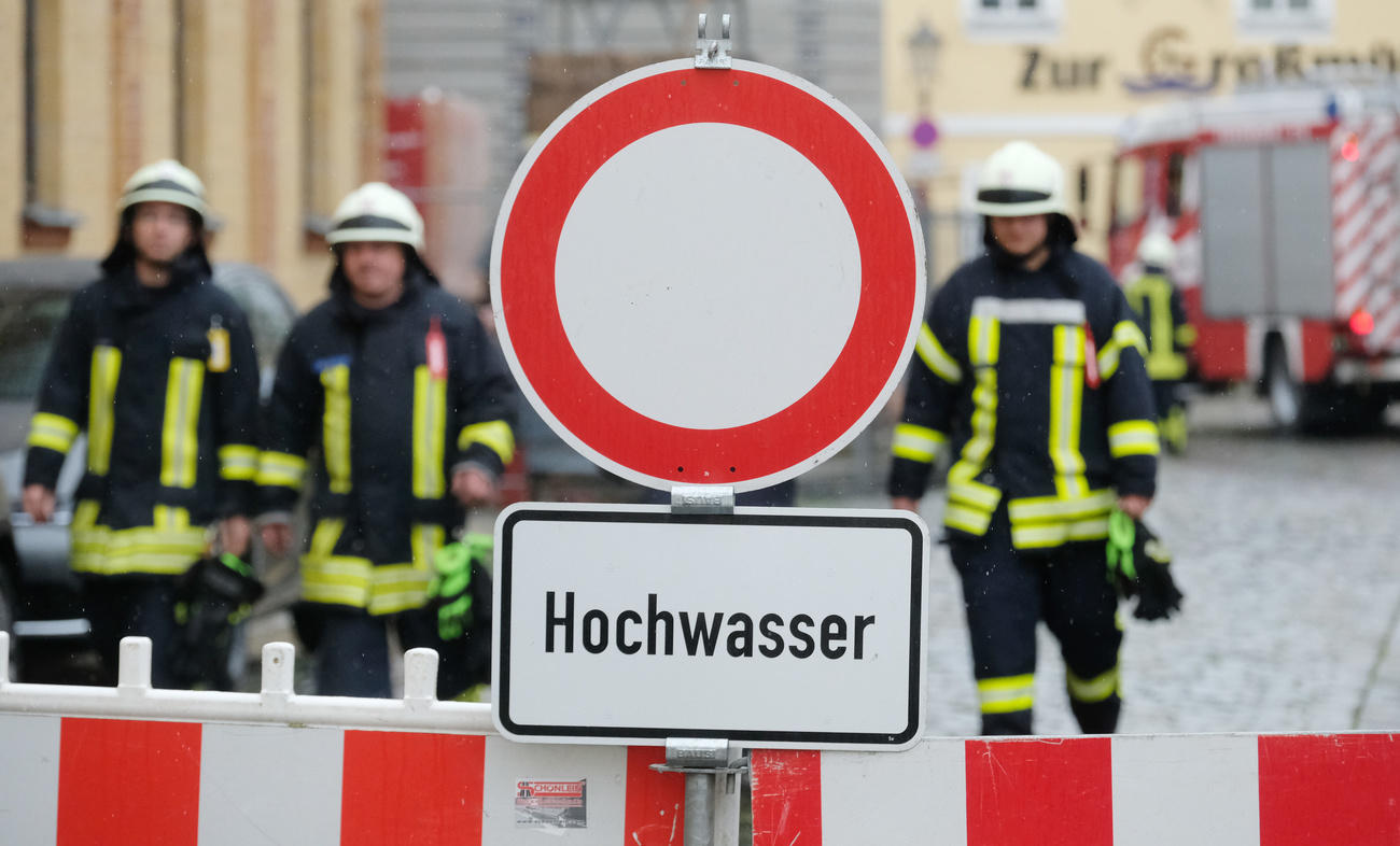 cartello hochwasser con pompieri in secondo piano