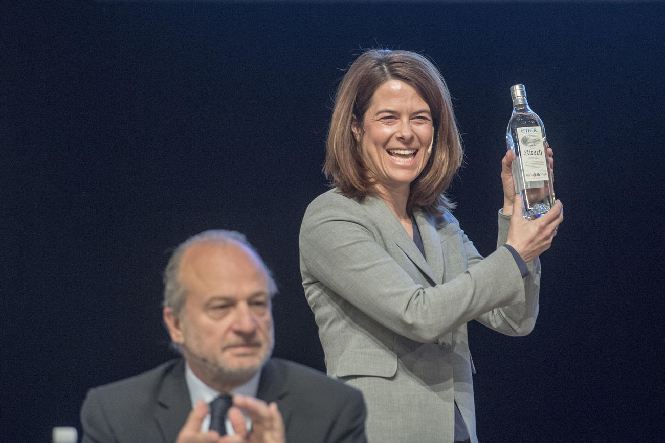 Woman smiling, holds up bottle of kirsch