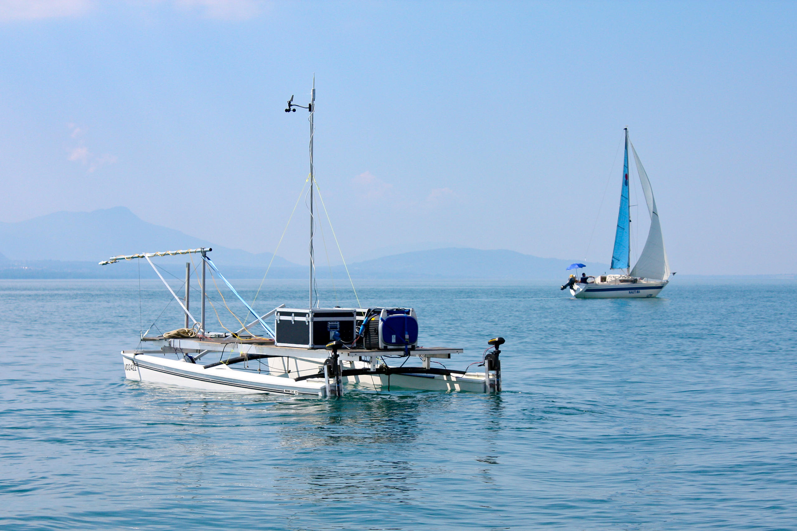 Catamarán en el lago Lemán y un velero al fondo