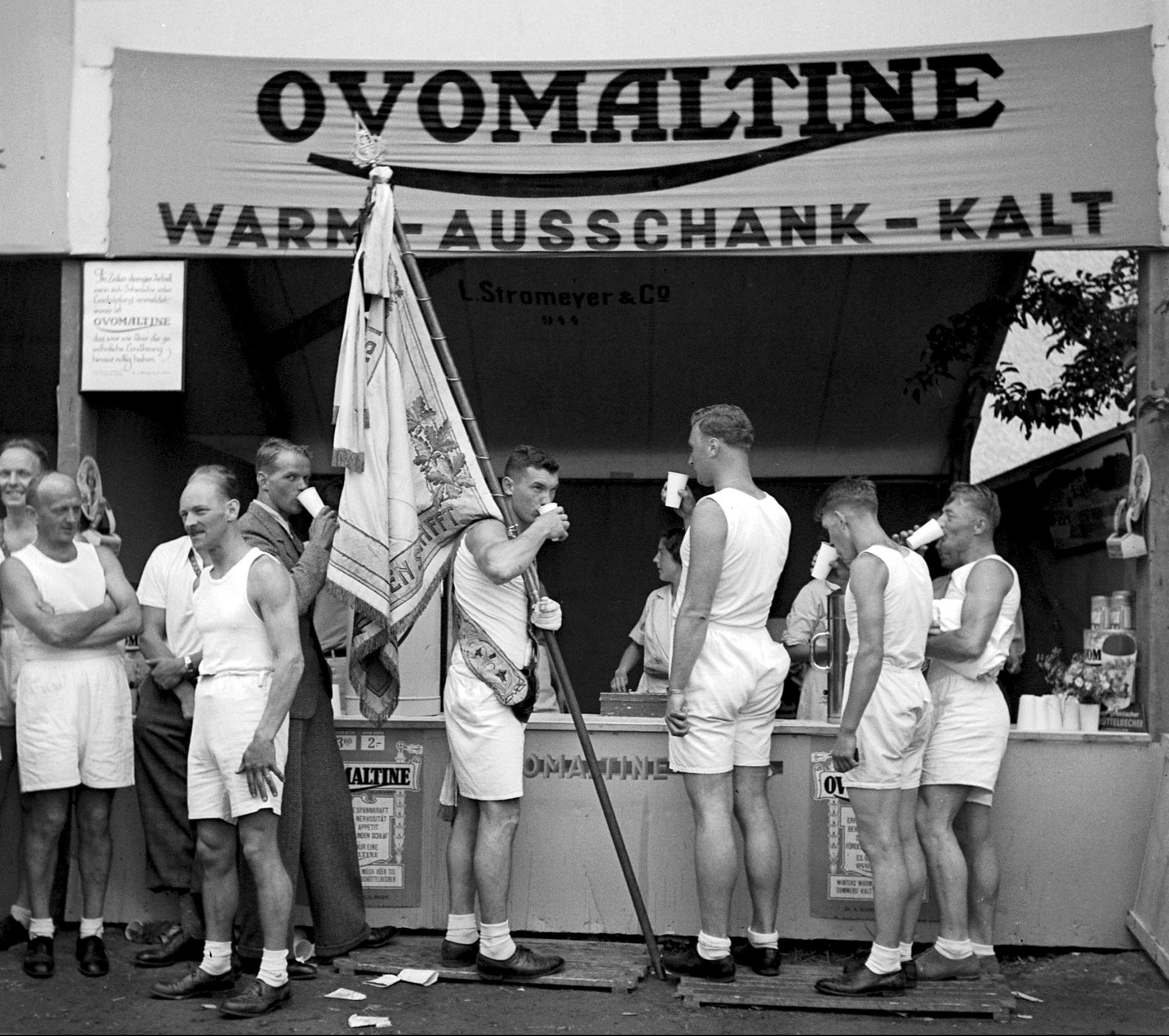 Gimnastas en el Festival Federal de Gimnasia de Winterthur recuperan fuerzas en el estand de Ovomaltine, en 1936.
