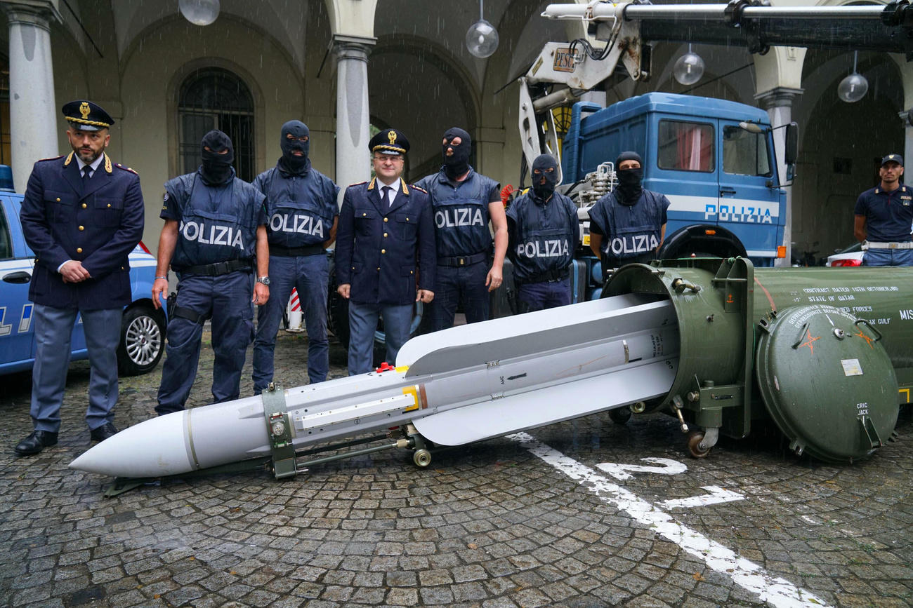 Police stand next to a missile seized at an airport hangar in northern Italy