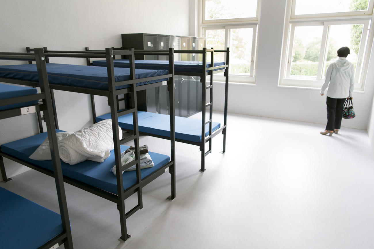 Room in asylum centre with empty beds and a visitor
