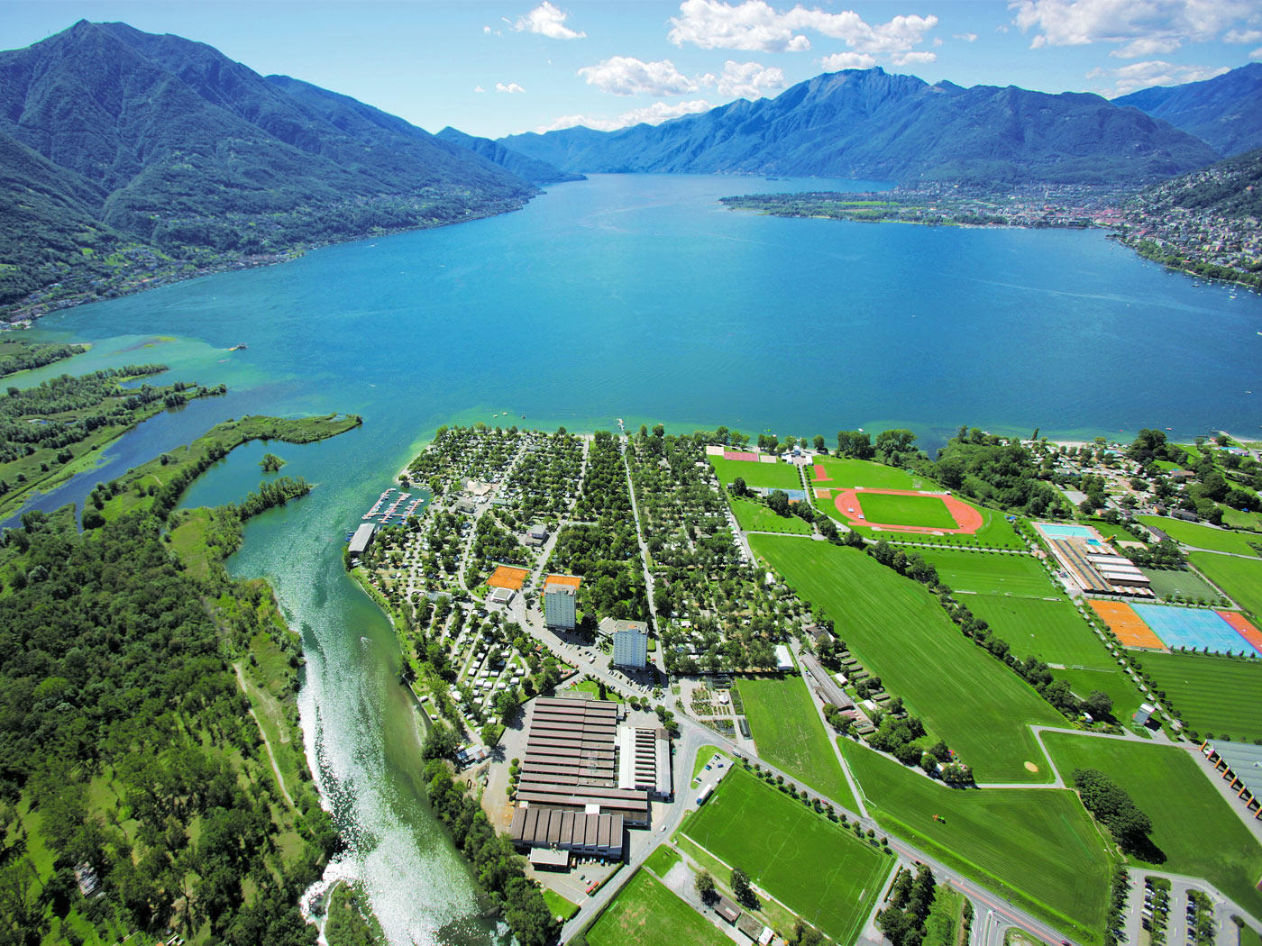 Farbfoto: See und Flussmündung, rechts daneben ein grosser Campingplatz