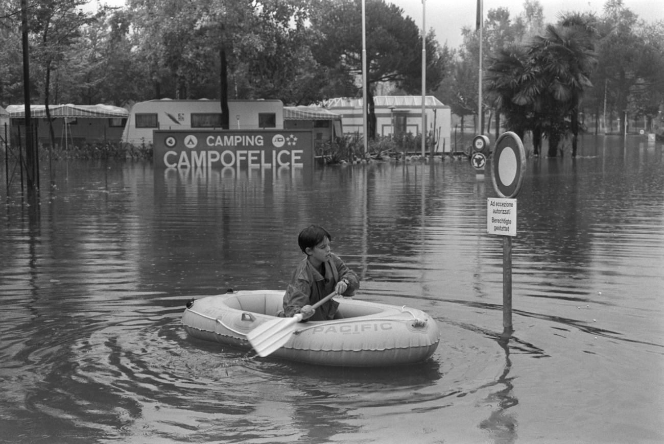 Kind auf Gummiboot auf dem Hochwasser neben einem Fahrverbot