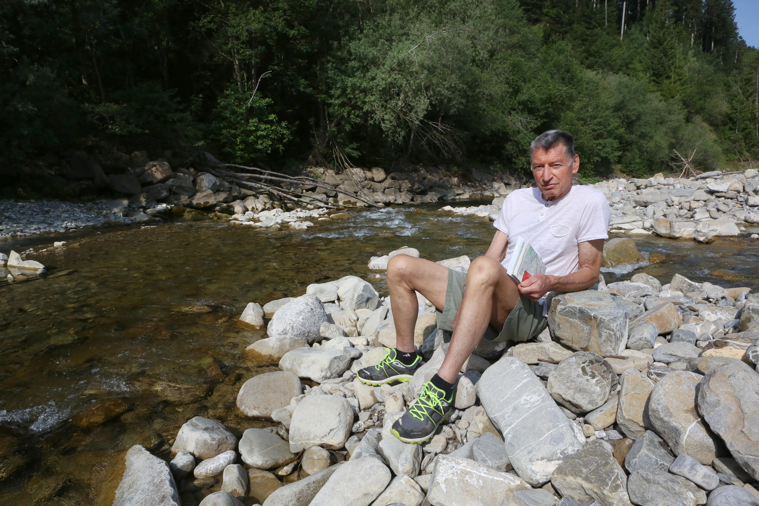 uomo seduto sui sassi a bordo fiume