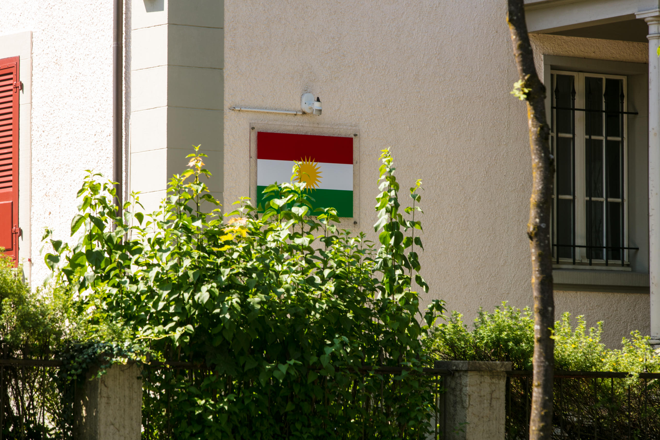 Eine an einer Hauswand angebrachte-rot-weiss-grüne Flagge mit einer Sonne in der Mitte.