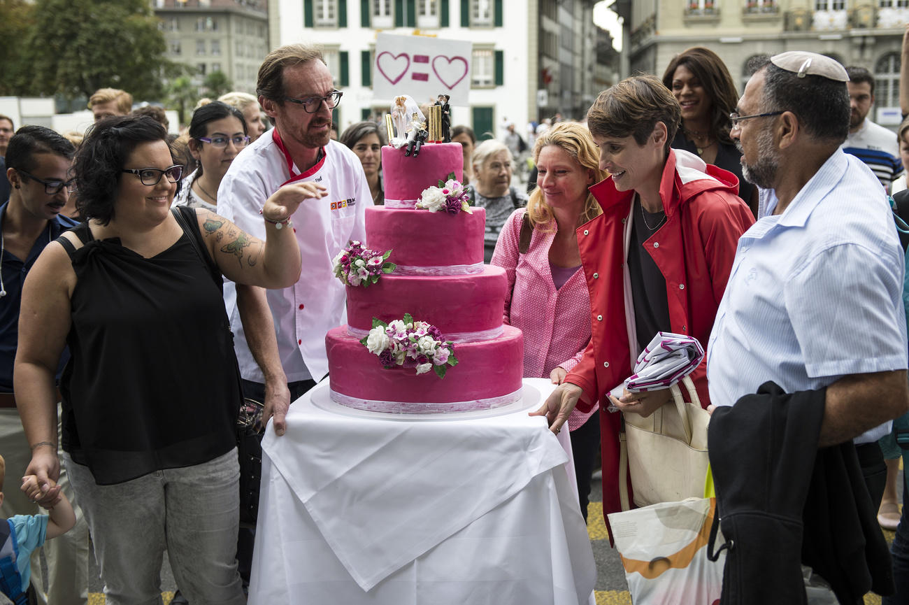 Grupo de personas en torno a una tarta nupcial de color rosa