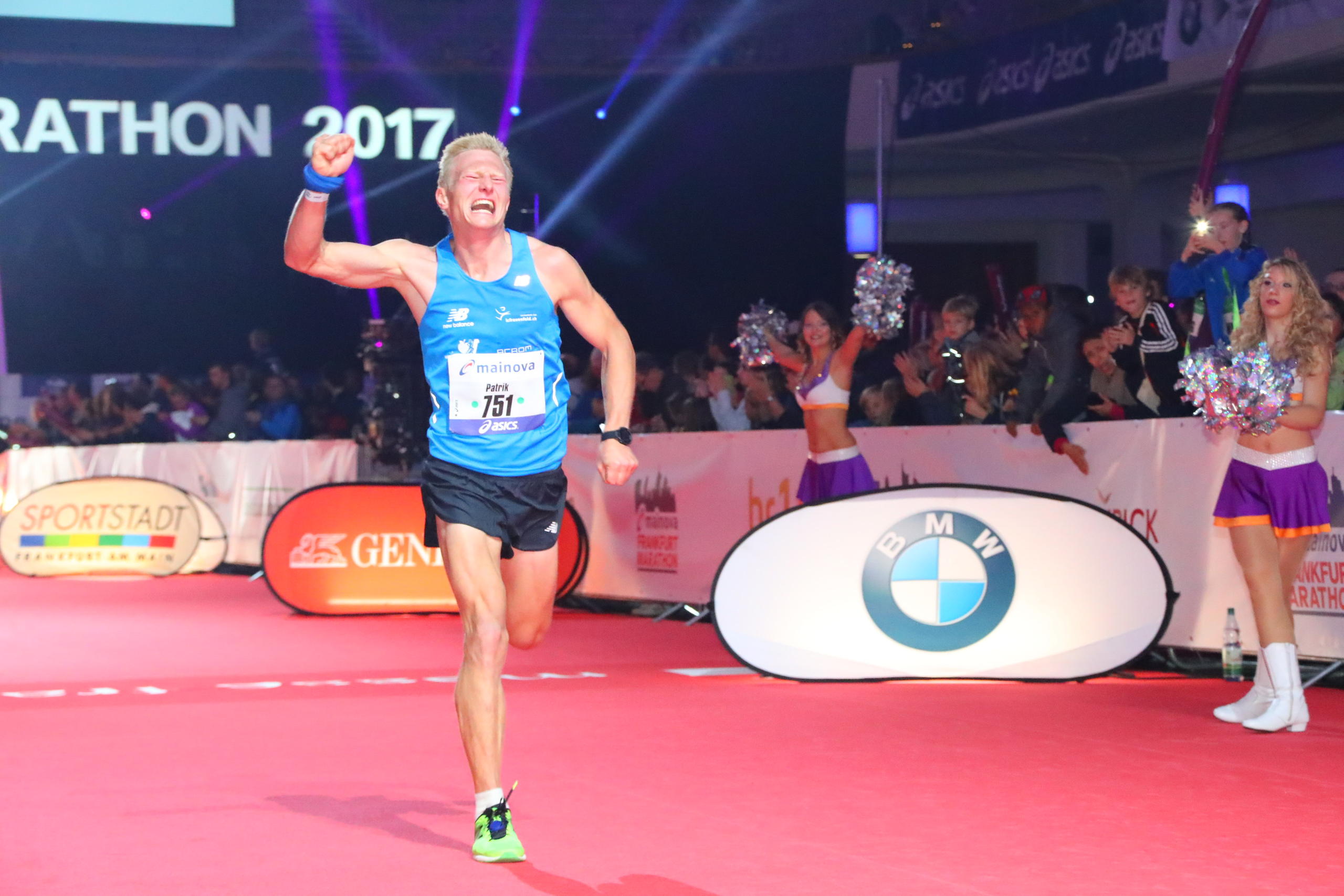 ガッツポーズをしながらゴールインするマラソン選手