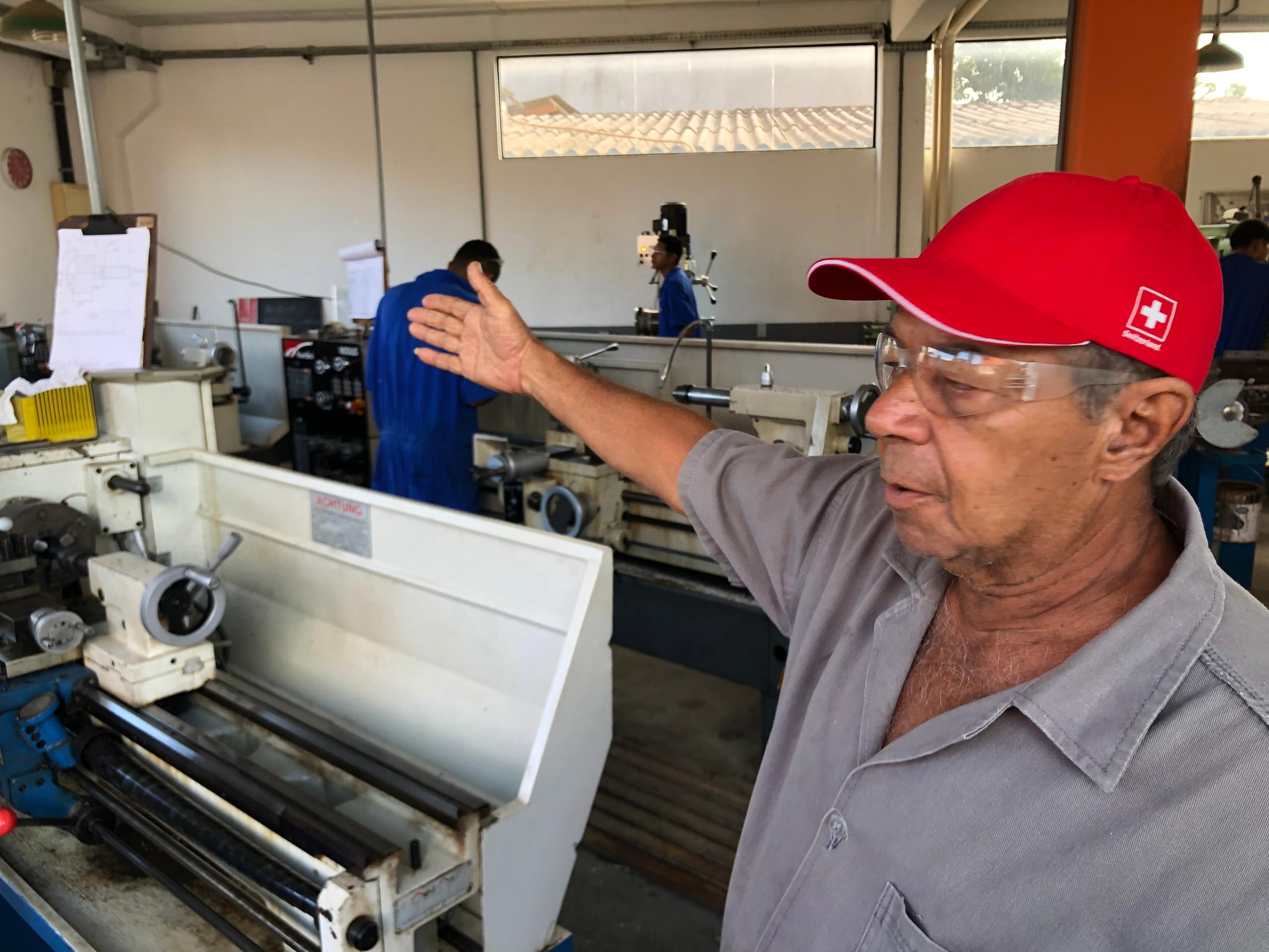 Homem com um boné vermelho frente a máquinas