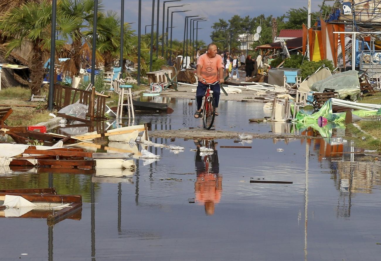 uomo in bici su una strada devastata