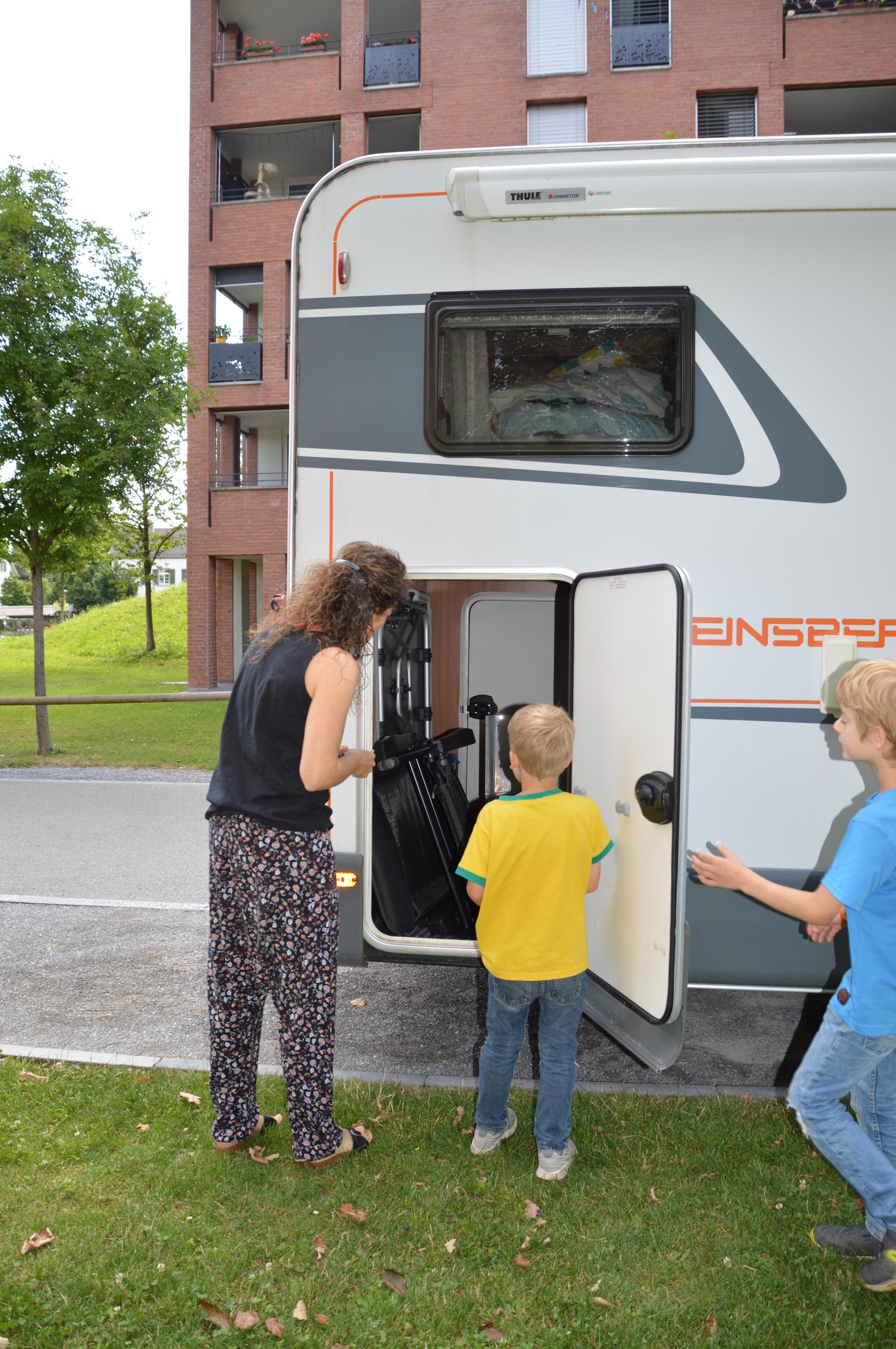 Aline mit zwei Kindern neben dem Wohlmobil