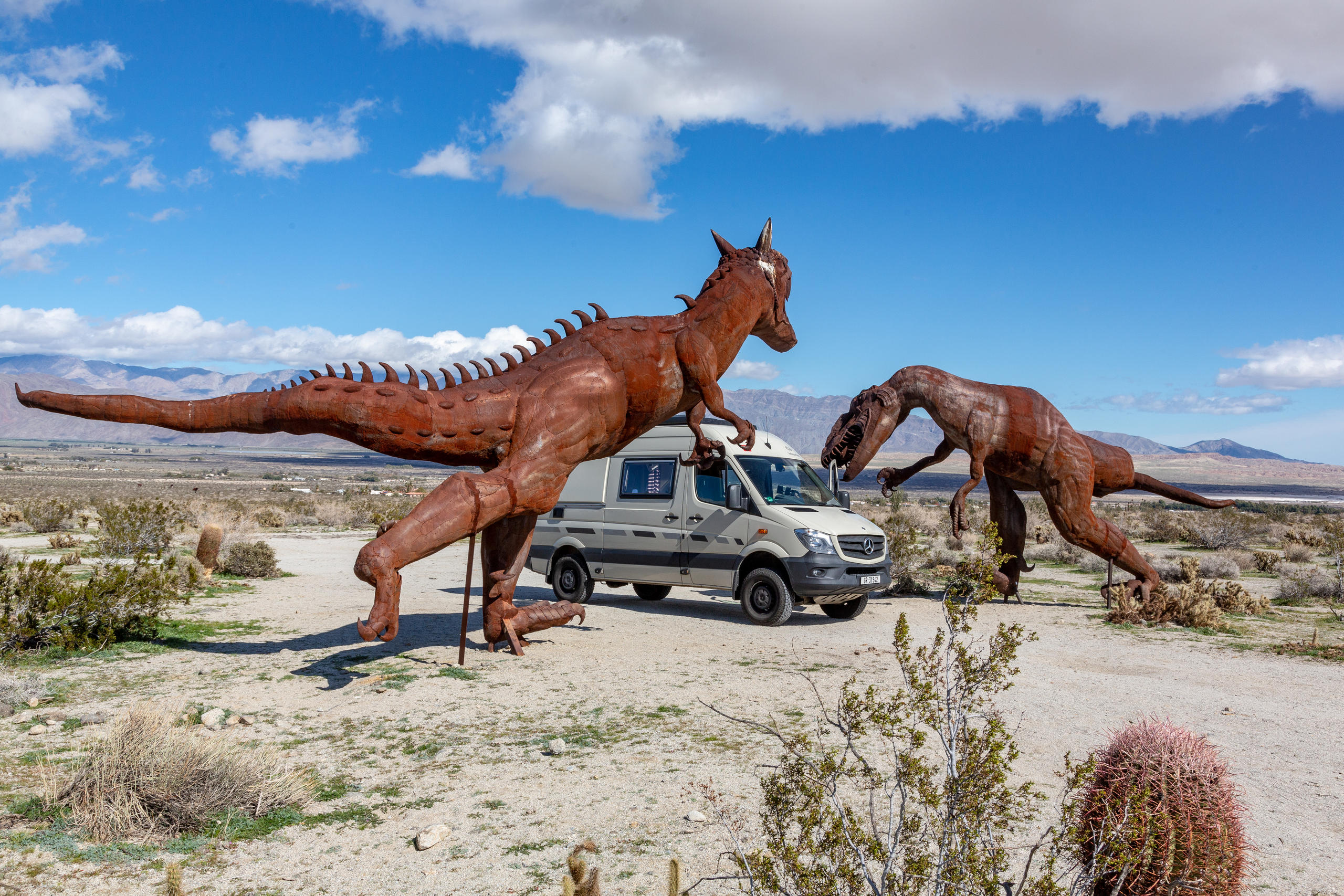 Van fährt an Dinosaurier-Statuen vorbei