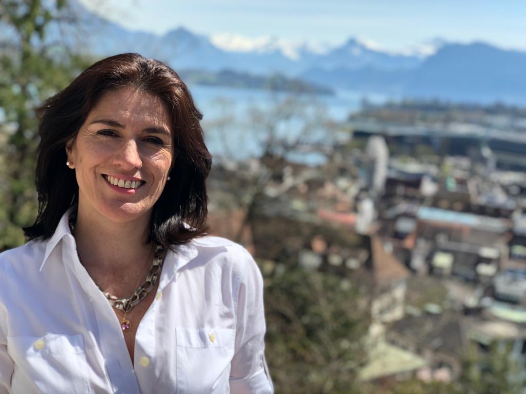 Primer plano de una mujer sonriente con un lago y los Alpes al fondo