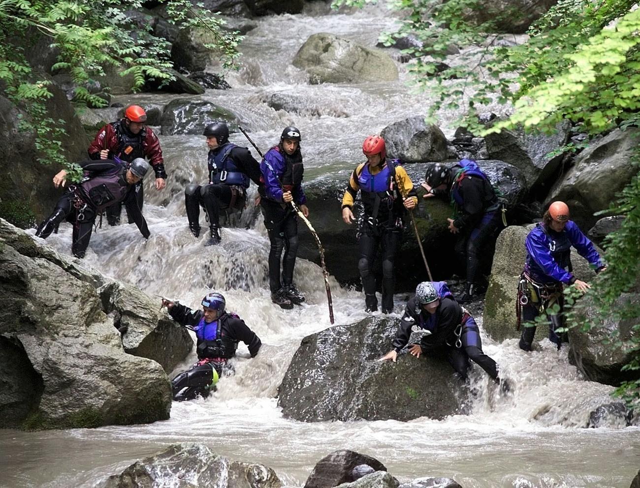 Rescuers stand in riverbed, some probing water with sticks