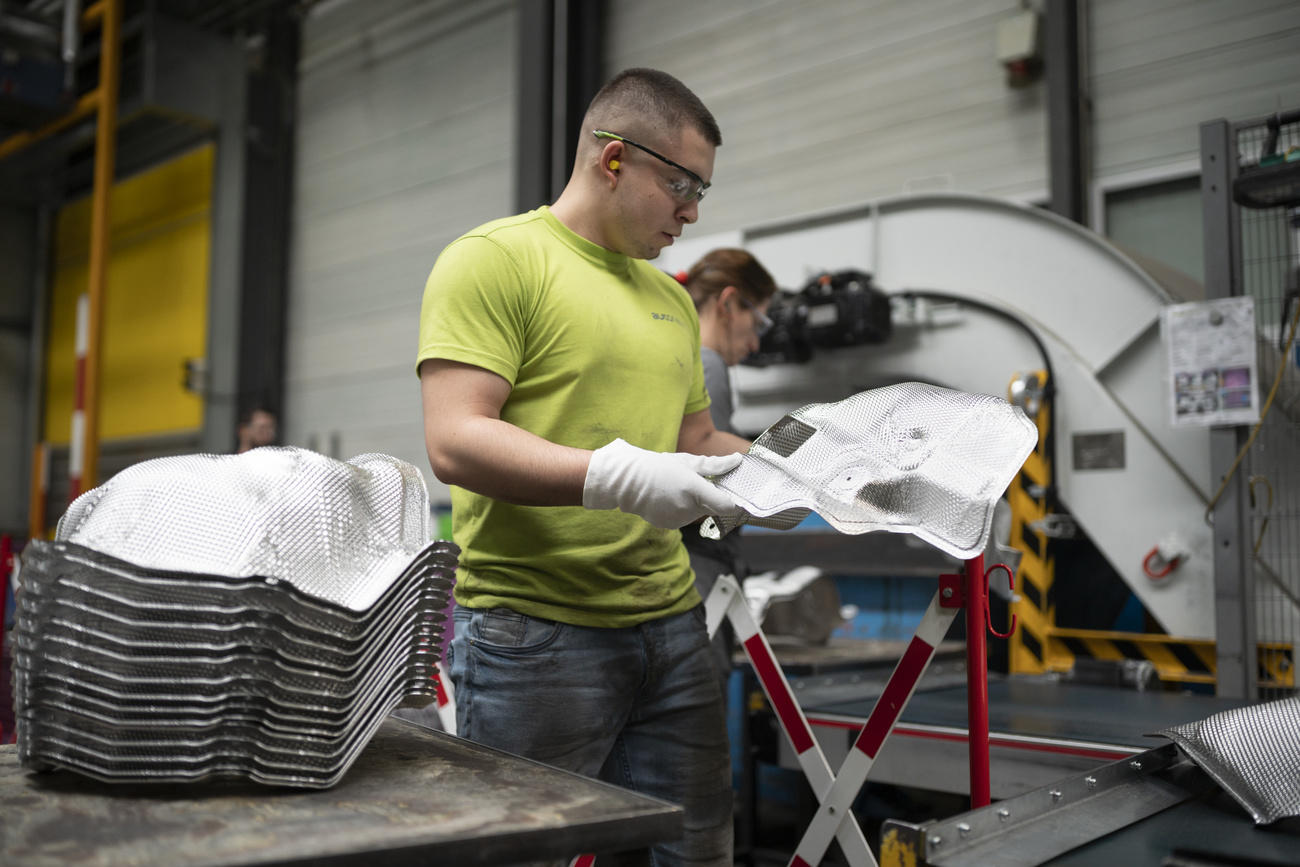 Ein Mann mit einer Schutzbrille und Handschuhen in einer Fabrik.