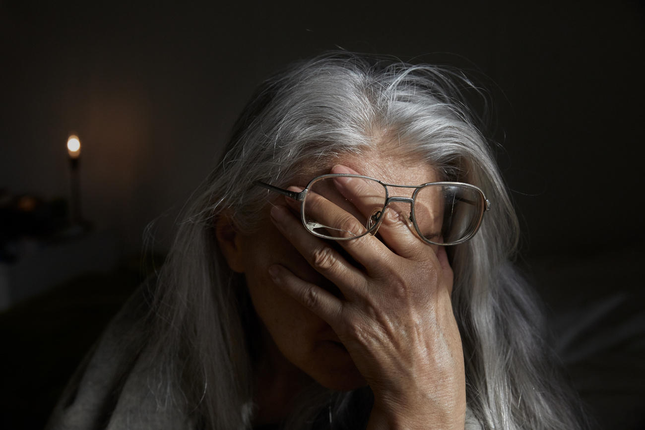 Eine betagte Frau legt die Hand vors Gesicht