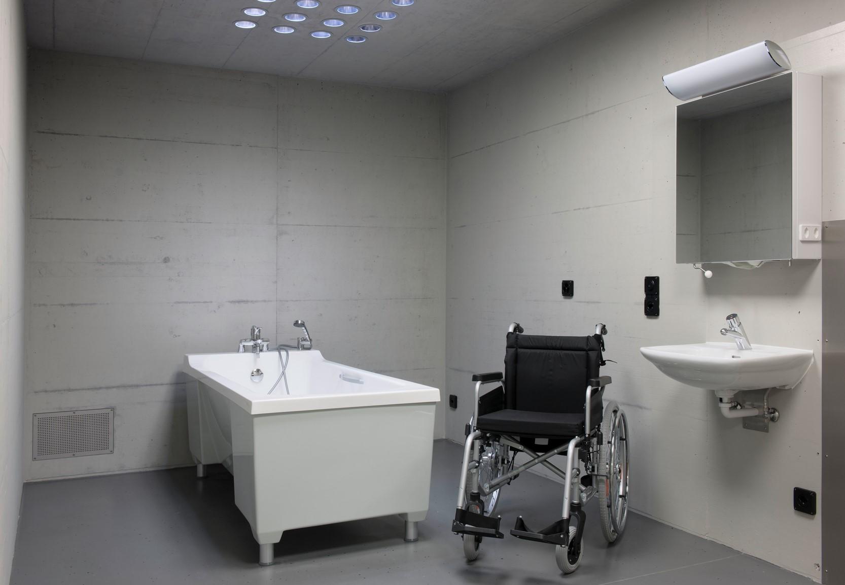 Chaise roulante et baignoire dans une cellule.