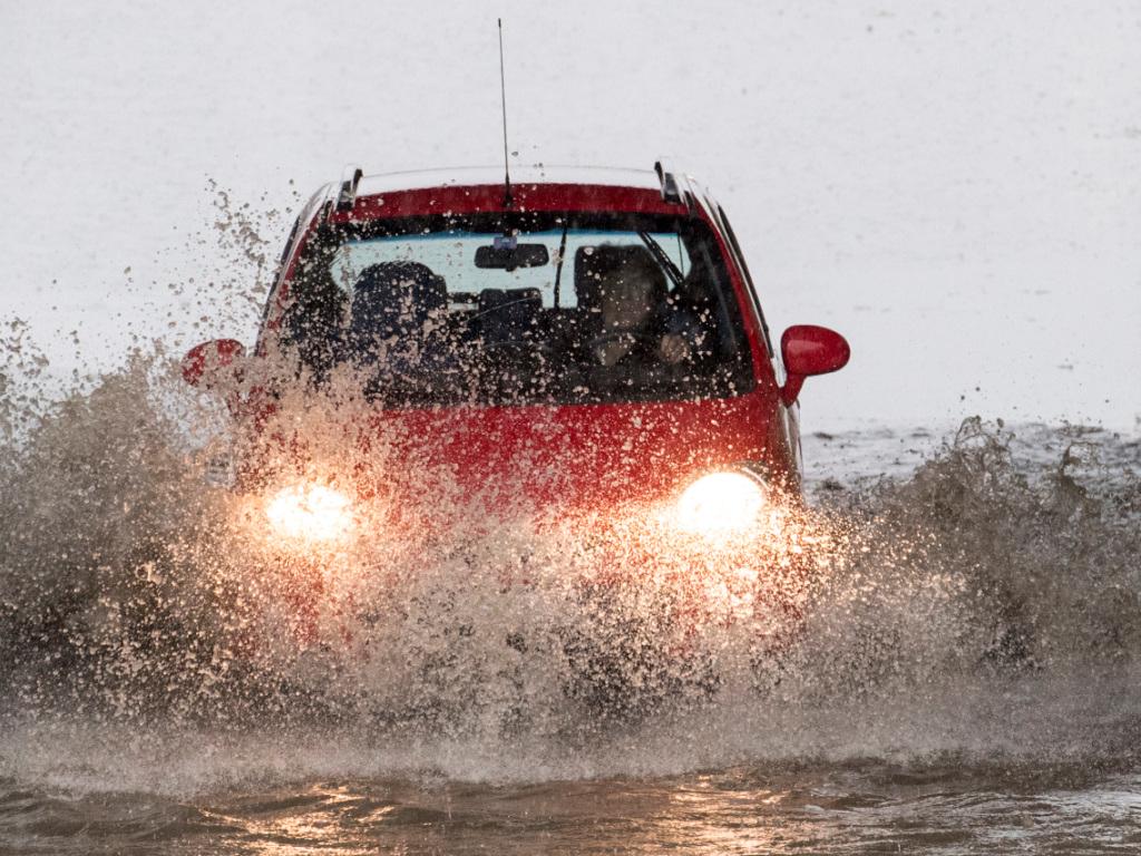 Ein Auto fährt durch eine grosse Pfütze