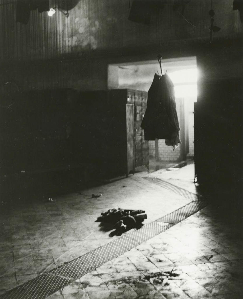 An abstract image of an object hanging on hooks and clothes lying on the ground. Light comes from the the background.