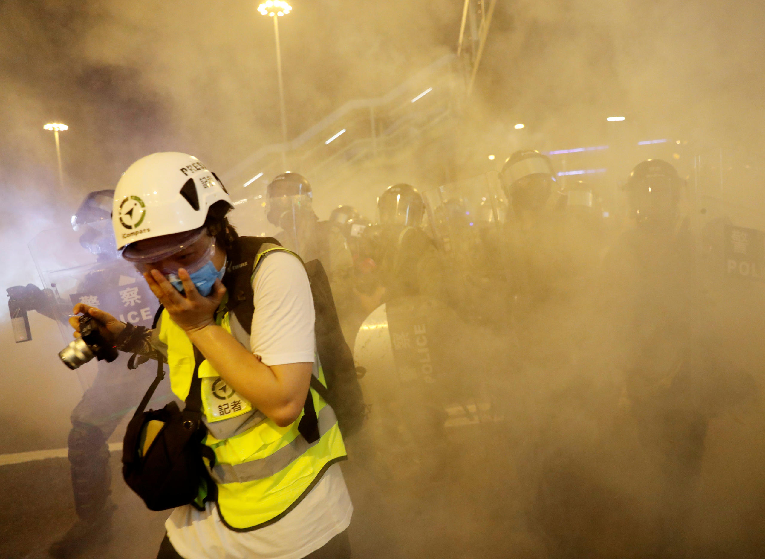 Un periodista se cubre la cara para protegerse del gas lacrimógeno