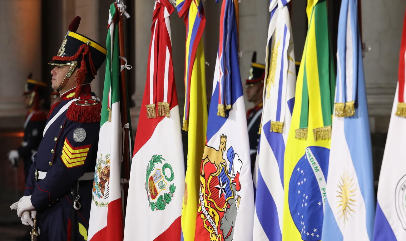 Un militare in alta uniforme, di guardia (d onore) accanto alle bandiere di alcuni Paesi sudamericani