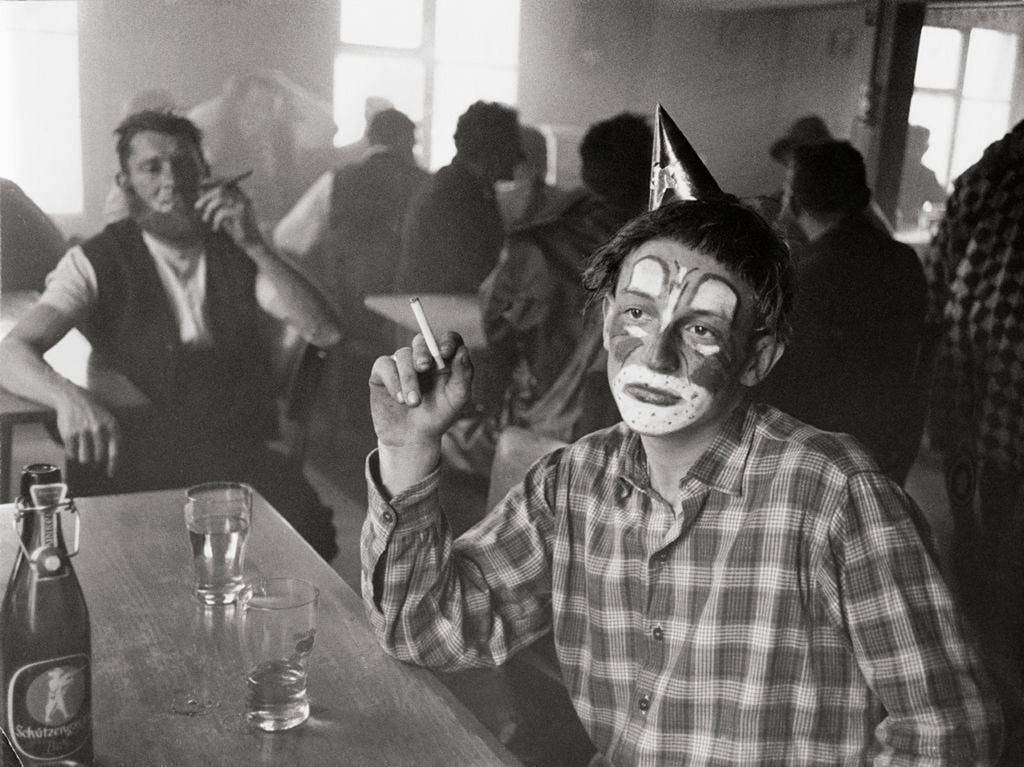 Un homme assis à un bar avec une visage grimmé en clown