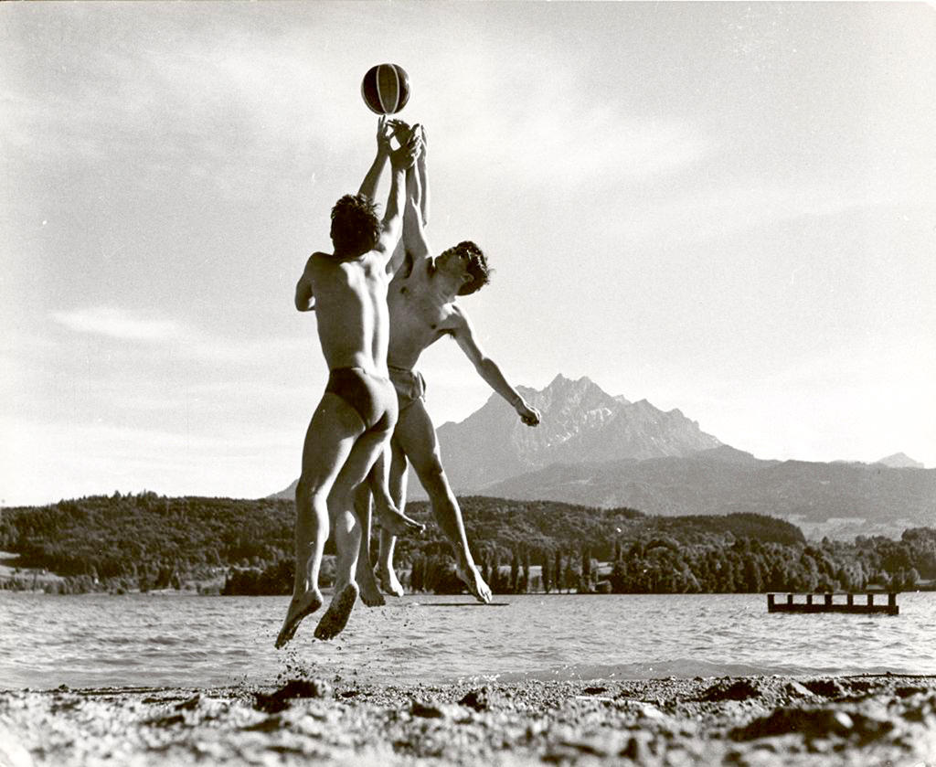 Two young men jump to catch the same ball.