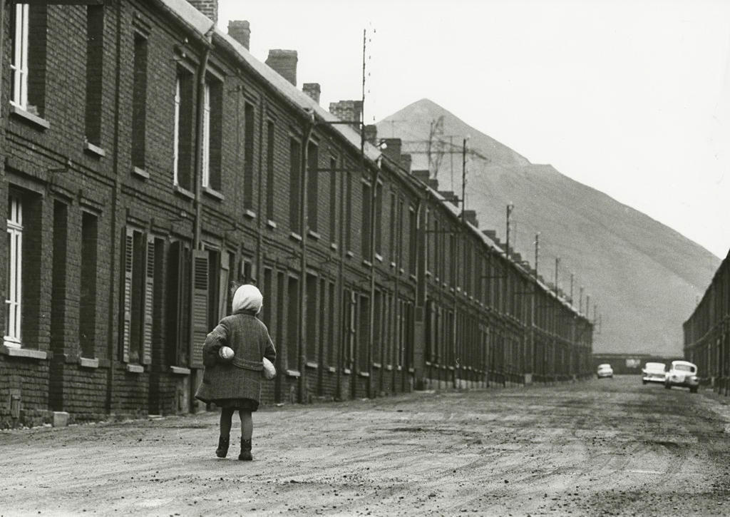 A young girl stands in a street alone.