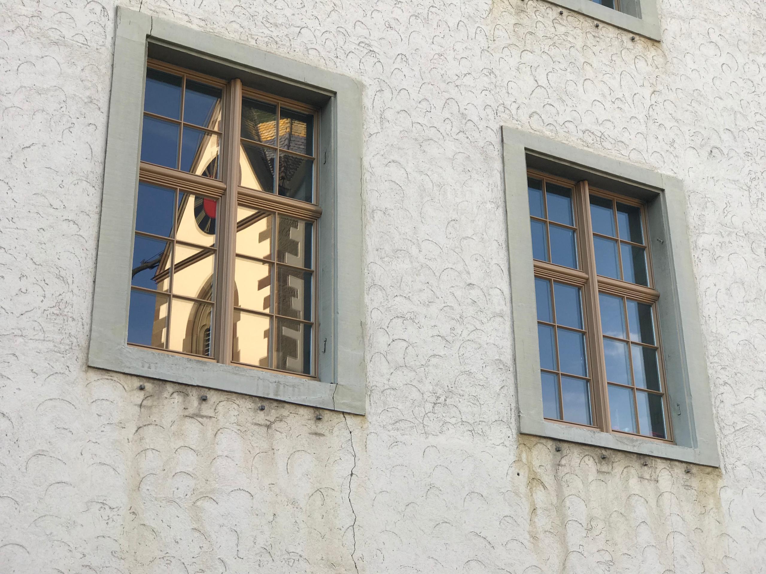 The church tower is reflected in the windows of the building housing the museum