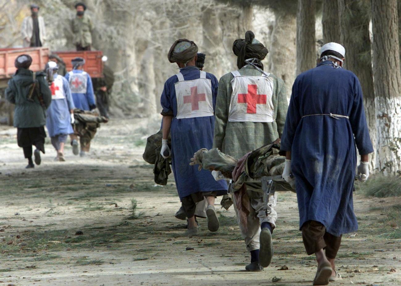 Local Afghan Red Cross workers carry dead Taliban fighters