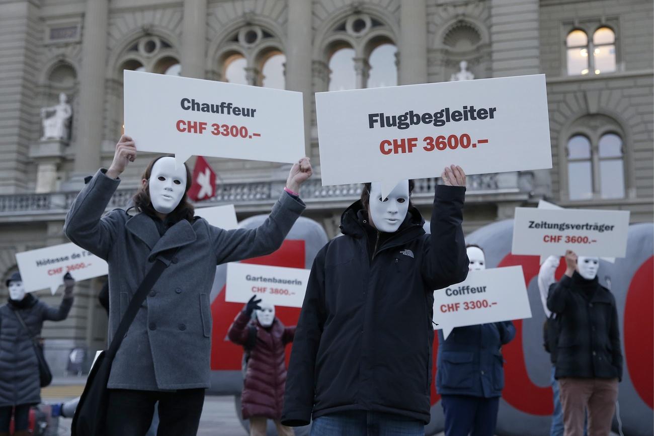 Demonstranten für Mindestlohn halten Schilder mit Löhnen verschiedener Berufe