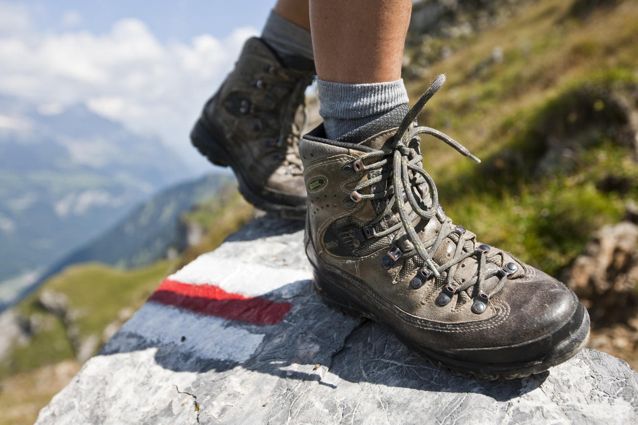 Botas de montaña encima de una piedra con una señalización de senderismo