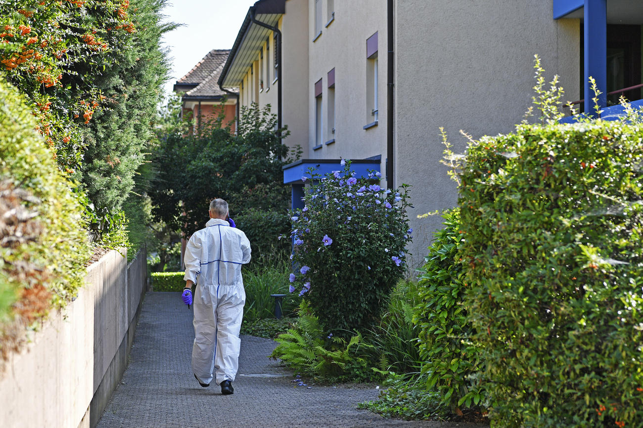 Un hombre en uniforme blanco, de espaldas, en una zona habitacional.