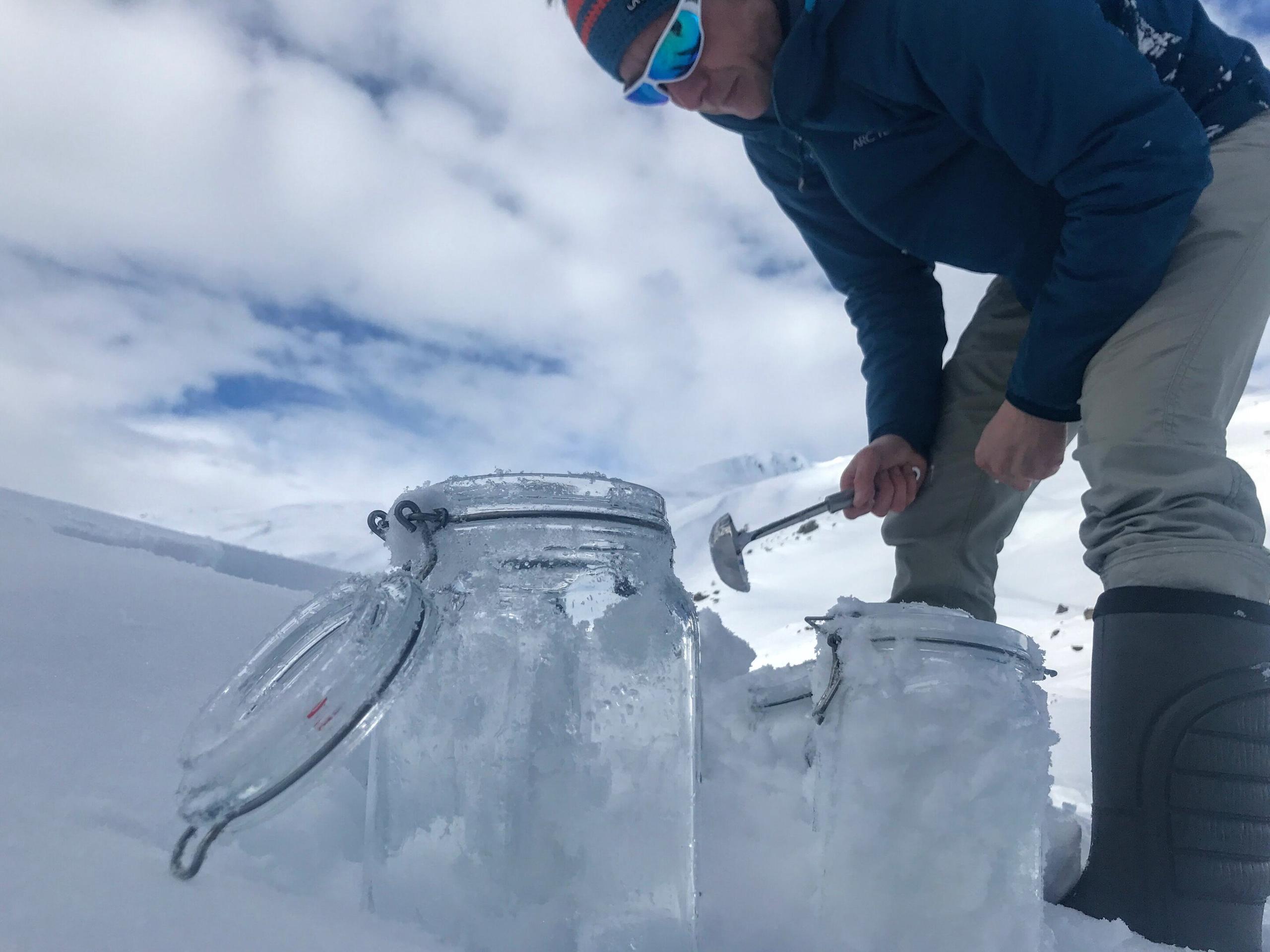 Fresh snow is filled with a chrome steel scoop into glass containers.