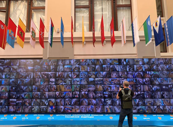 Un hombre saca fotos a una pared llena de pantallas