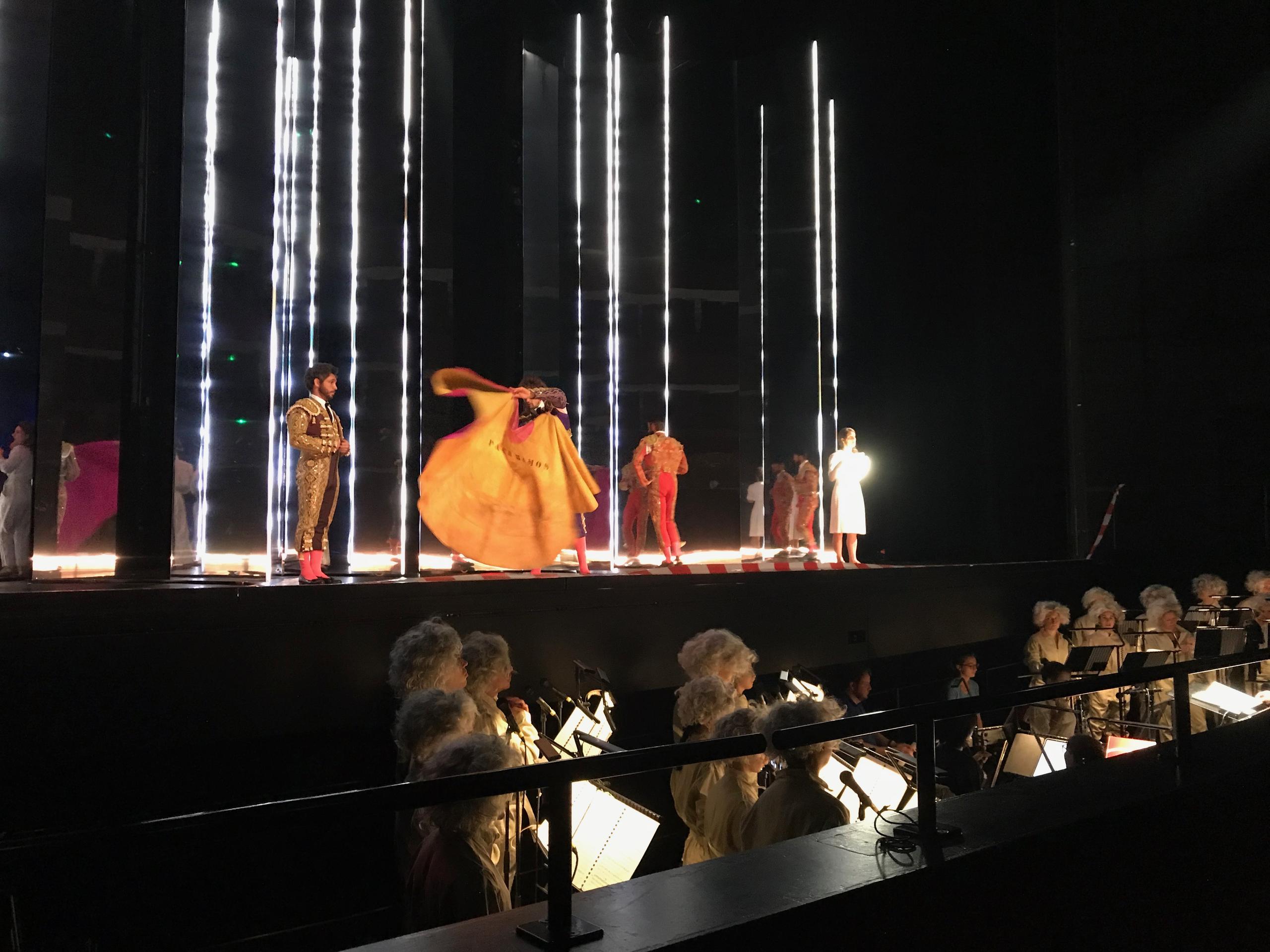 Performers on stage, choir with Einstein wigs in the alcove