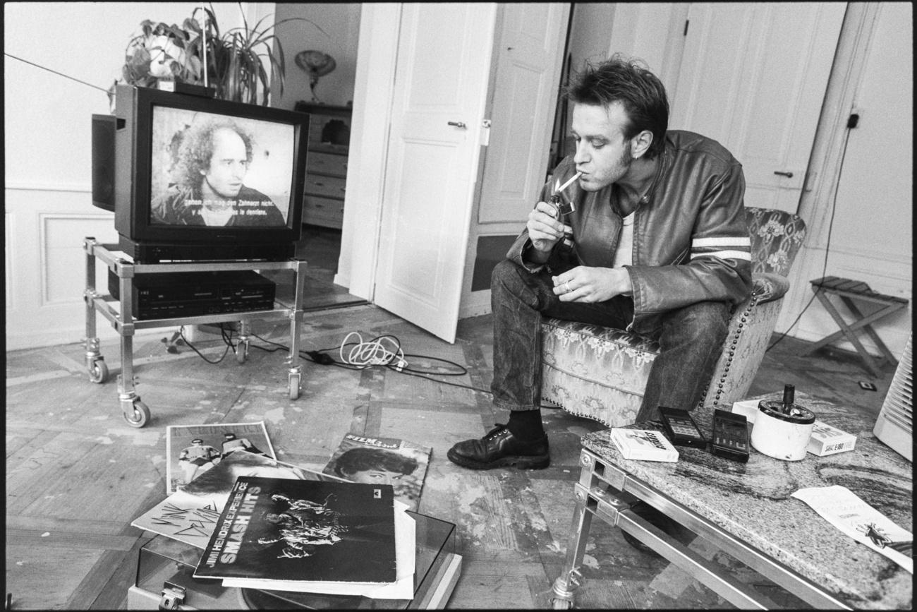 Un homme fume en regardant la télévision