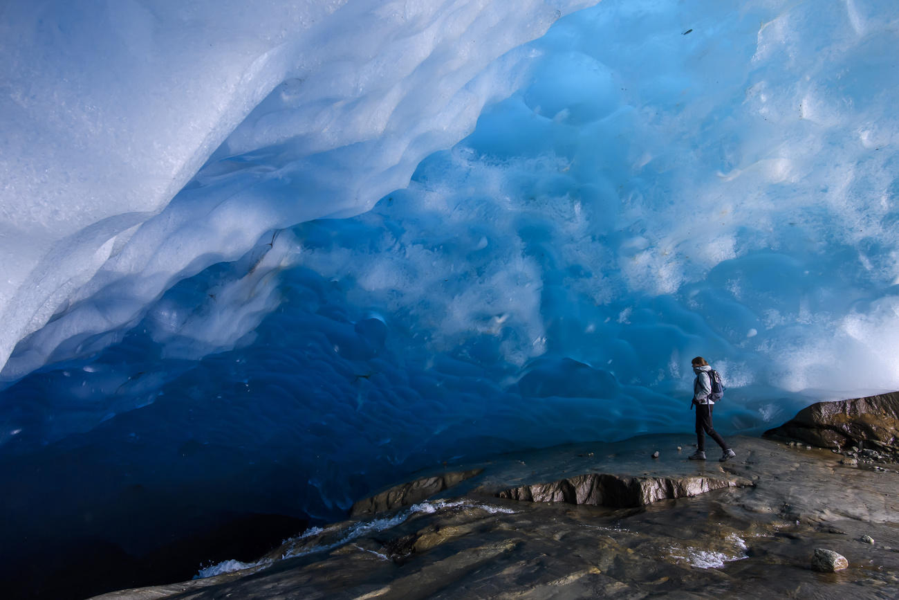 A person walks under a translucent part of a glacier