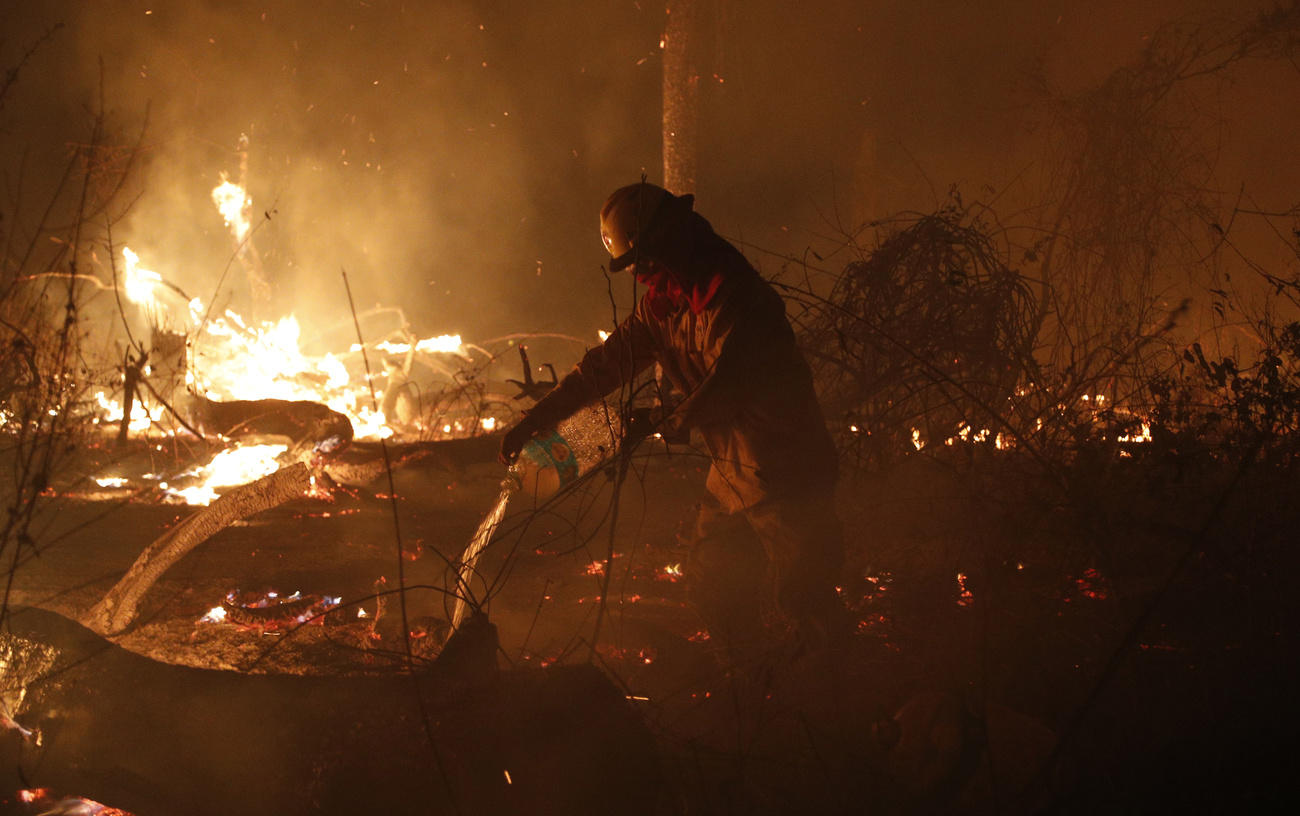 Un pompiere circondato dal fuoco nella foresta amazzonica