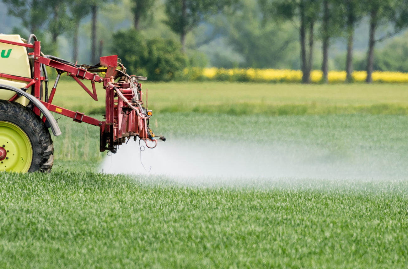 Traktor sprüht Pestizide auf ein Feld